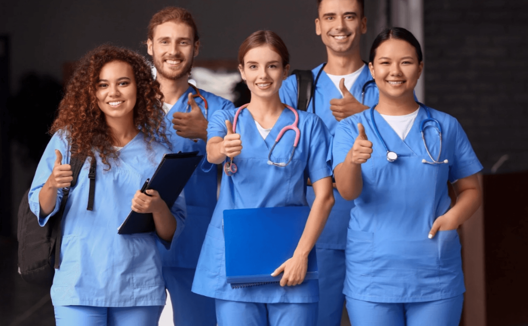 Healthcare professionals in scrubs giving a thumbs-up.
